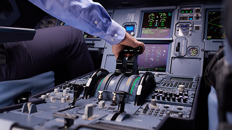 A man operates the thrust control in an aircraft cockpit