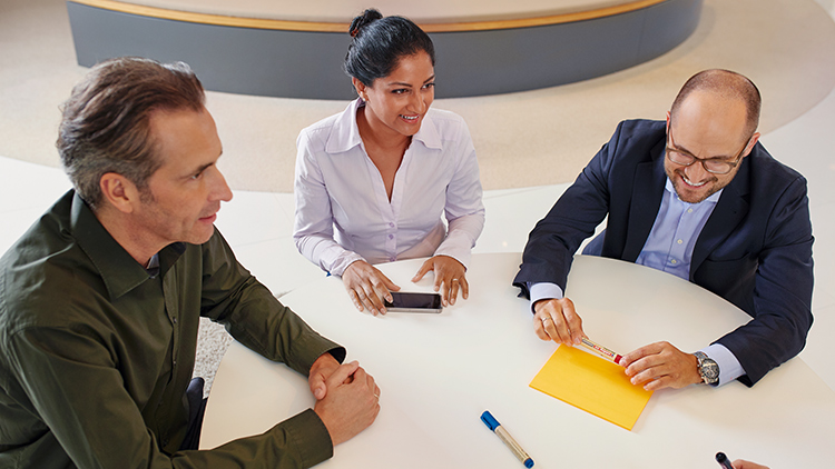 Three smiling people sitting at a round table