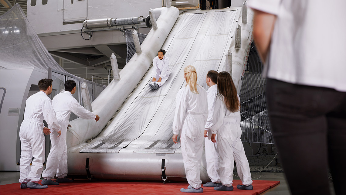 Participants of a Safety and Emergency Training practice the use of a rescue slide on a simulator