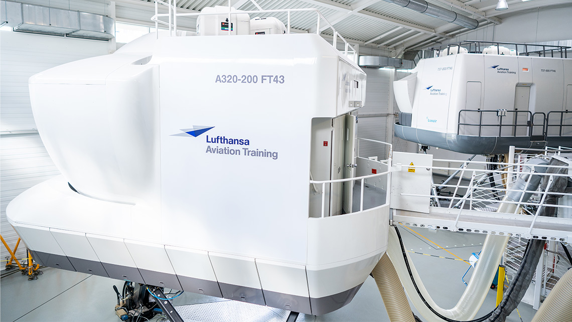 Two flight simulators from Lufthansa Aviation Training are located in a hangar.